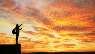 Gün batımında dağda duran turist silueti. İşaret parmağının yönünü gösterir