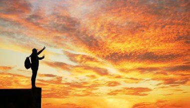 Gün batımında dağda duran turist silueti. İşaret parmağının yönünü gösterir