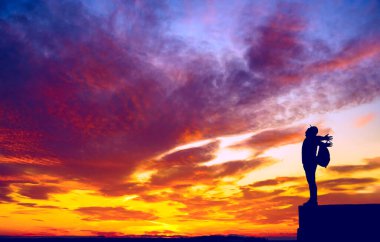 Sırt çantalı sırt çantalı sırt çantalı silueti vadinin yukarısındaki kayalık manzarada duruyor.. 