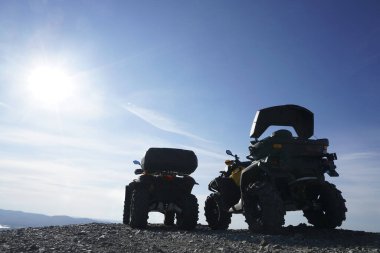 Dağın tepesinde mavi bulutlu arka planda dörtlü bisiklet siluetleri. gün ışığı. 