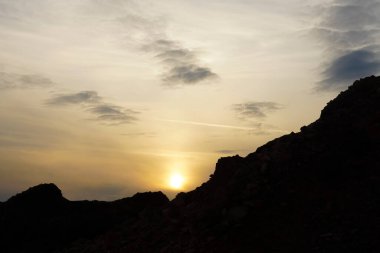 Gün doğumunda parlayan gökyüzünde dağlar. Doğa geçmişi. Dağların siluetiyle güzel bir gün batımı.
