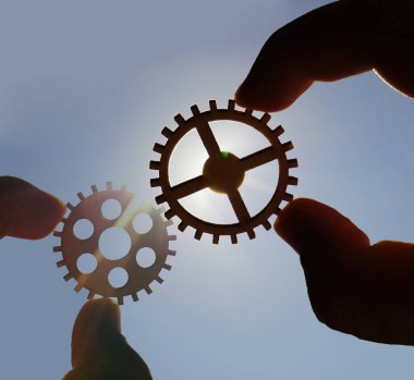 Metal dişlileri tutan eller. takım çalışması fikri