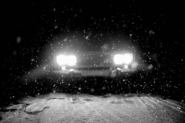 一辆汽车站在雪地里 冬天漆黑的夜晚 汽车在雪地的路上行驶 大雪过后 前灯明亮地照亮了小径和森林 — 图库照片