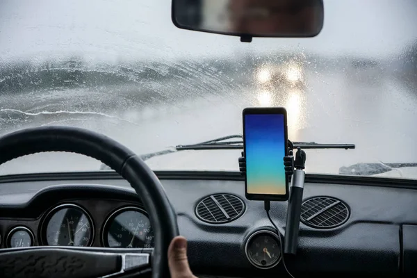smartphone white blank screen inside the car. Mock up image.  blank colorful screen mobile smart phone inside a car in rainy day, touching screen or texting, copy space for your advertisement.