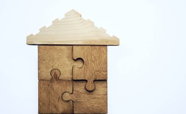  Beyaz arka planda izole edilmiş bulmacalardan yapılmış ahşap bir ev. Yapbozun doğal malzemesinden yapılmış ahşap ev. Ahşap ev şeklinde bir bulmaca. satılık ya da kiralık