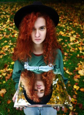 Aynada kendi yansıması olan genç kızıl saçlı bir kadının portresi. f