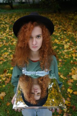 Aynada kendi yansıması olan genç kızıl saçlı bir kadının portresi. f