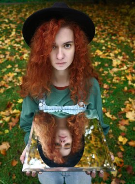 Aynada kendi yansıması olan genç kızıl saçlı bir kadının portresi. f