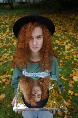 Aynada kendi yansıması olan genç kızıl saçlı bir kadının portresi. f