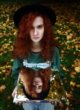 Aynada kendi yansıması olan genç kızıl saçlı bir kadının portresi. f