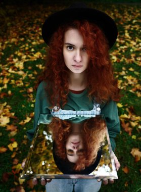 Aynada kendi yansıması olan genç kızıl saçlı bir kadının portresi. f