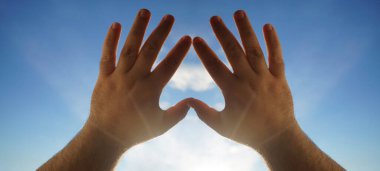 Kalp sembolü gökyüzü arka planındaki eller, Aşk ya da Sağlık kavramı. Kavramsal insan, erkek ya da kadın, birbirine aşık, sevgililer günü şekli ya da mavi gökyüzü arka planındaki kalp sembolü.