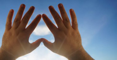 Kalp sembolü gökyüzü arka planındaki eller, Aşk ya da Sağlık kavramı. Kavramsal insan, erkek ya da kadın, birbirine aşık, sevgililer günü şekli ya da mavi gökyüzü arka planındaki kalp sembolü.