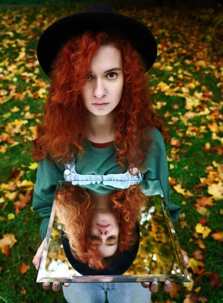 Aynada kendi yansıması olan genç kızıl saçlı bir kadının portresi. f