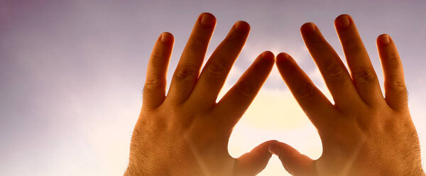 Heart symbol from hands on the sky background, Concept for Love or Health. Concept conceptual human male or man and woman hands in love, Valentines shape or symbol of heart on blue sky background