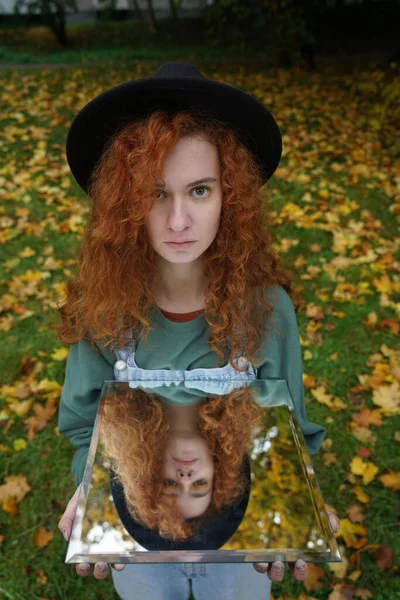 Aynada kendi yansıması olan genç kızıl saçlı bir kadının portresi. f