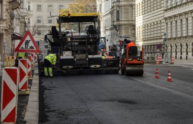 İnşaat alanı yeni asfalt yol kaldırımları, yol inşaat işçileri ve yol yapım makineleri sahnesi inşa ediyor. İnşaat alanı manzarası. VIENNA, AUSTRIA