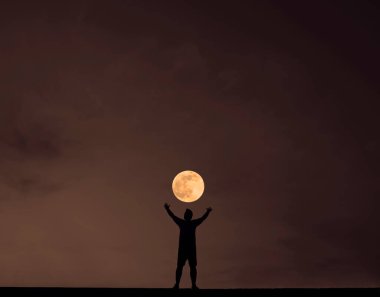 Gece karanlığında elleri havada genç bir adamın silueti. gece sahnesi.