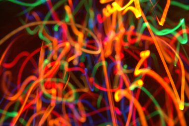 Siyah arkaplana odaklanmış soyut LED ışıklandırması. Karanlık arka planda kaotik renk ışıkları çizgileri. Renkli ışıklar siyah boşlukta hareket eder. Gece kulübü Arkaplanı.