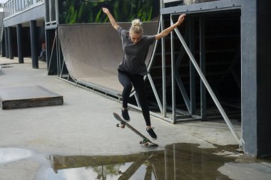 Kot pantolonlu genç bir kadın kaykaylı bir ollie yapıyor.