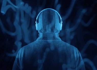 Kapüşonlu, beyaz kulaklıklı, tanınmayan bir adam. Geriye, dikiz aynasına. Siyah arka planda izole edilmiş. yüksek sesli müzik