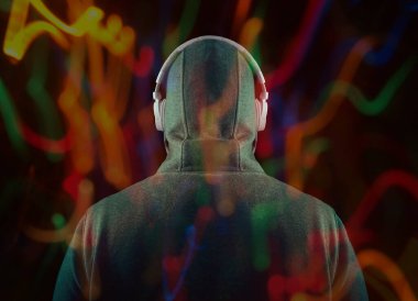 Kapüşonlu, beyaz kulaklıklı, tanınmayan bir adam. Geriye, dikiz aynasına. Siyah arka planda izole edilmiş. yüksek sesli müzik