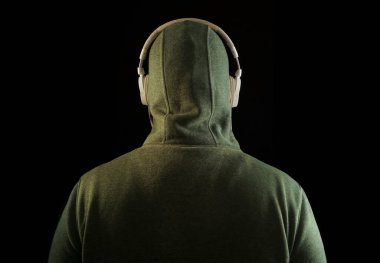 Kapüşonlu, beyaz kulaklıklı, tanınmayan bir adam. Geriye, dikiz aynasına. Siyah arka planda izole edilmiş. yüksek sesli müzik