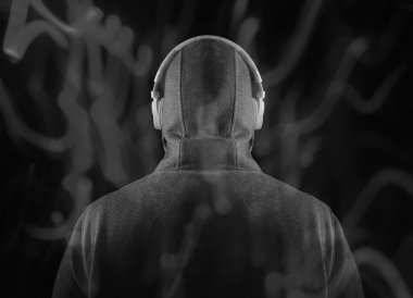 Kapüşonlu, beyaz kulaklıklı, tanınmayan bir adam. Geriye, dikiz aynasına. Siyah arka planda izole edilmiş. yüksek sesli müzik