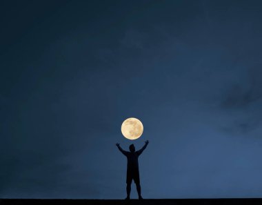 Gece karanlığında elleri havada genç bir adamın silueti. gece sahnesi.
