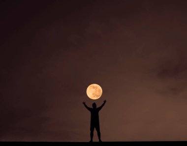 Gece karanlığında elleri havada genç bir adamın silueti. gece sahnesi.
