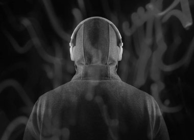 Kapüşonlu, beyaz kulaklıklı, tanınmayan bir adam. Geriye, dikiz aynasına. Siyah arka planda izole edilmiş. yüksek sesli müzik