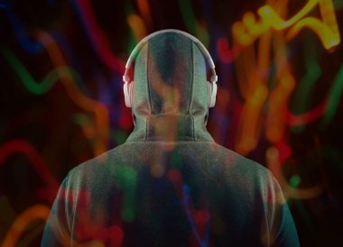 Kapüşonlu, beyaz kulaklıklı, tanınmayan bir adam. Geriye, dikiz aynasına. Siyah arka planda izole edilmiş. yüksek sesli müzik