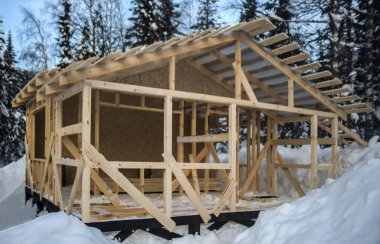Kışları ahşap bir evin çatısı inşa edilir. Kış mevsimi. Karlı bir konutta inşaat halindeki kare çerçeveli ev. Vahşi orman. Kar yağdıktan sonra.