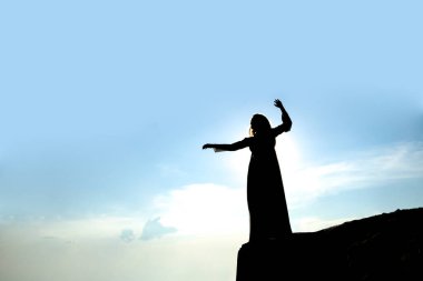 Güzel bir kadının silueti dağın kenarında duruyor. 