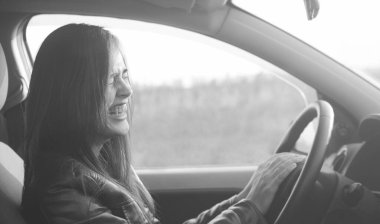 Modern arabanın içinde oturan güzel esmer kadın. İspanyol kız direksiyonun arkasındaki koltukta oturuyor.