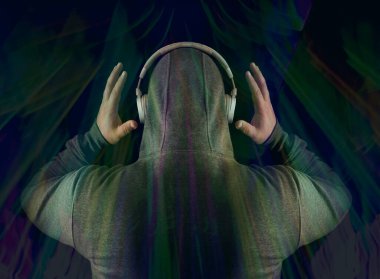 Kapüşonlu, beyaz kulaklıklı, tanınmayan bir adam. Geriye, dikiz aynasına. Siyah arka planda izole edilmiş. yüksek sesli müzik