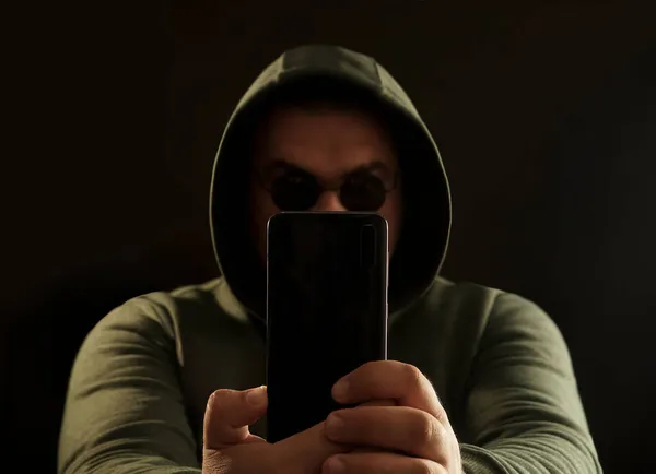 Człowiek Kapturze Patrzy Smartfona Mężczyzna Okularach Kapturze Pisze Wiadomość Przez — Zdjęcie stockowe