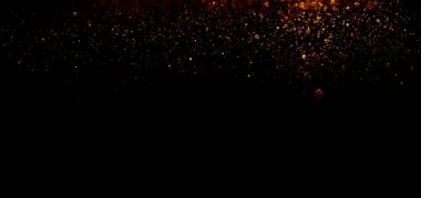 Siyah arka planda altın parıldayan sihirli altın tozu. Koyu arkaplan üzerindeki parçacıklar