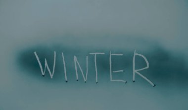 Kış. Donmuş cam harfler. Donmuş pencere yüzeyinde kış haberi var. Kış havası.