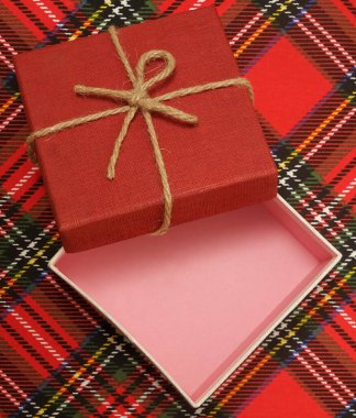 Noel arifesi kavramı - kırmızı kareli masa örtüsü üzerinde açık hediye kutusu. Ekose yün kumaş arka planda Mutlu Noeller 