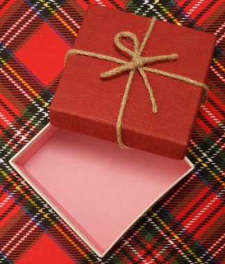 Noel arifesi kavramı - kırmızı kareli masa örtüsü üzerinde açık hediye kutusu. Ekose yün kumaş arka planda Mutlu Noeller 