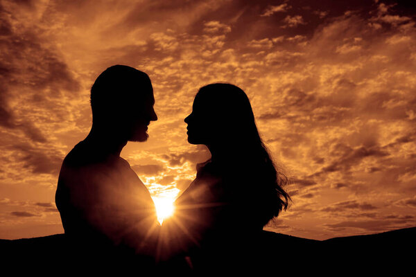 Silhouette of Happy Young Couple love Outside at Sunset. happy man and woman in sunlight evening sky in mountains. 