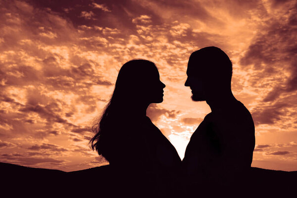 Silhouette of Happy Young Couple love Outside at Sunset. happy man and woman in sunlight evening sky in mountains. 