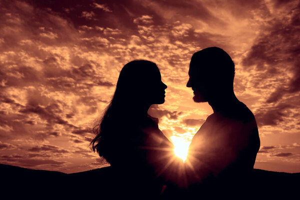 Silhouette of Happy Young Couple love Outside at Sunset. happy man and woman in sunlight evening sky in mountains. 