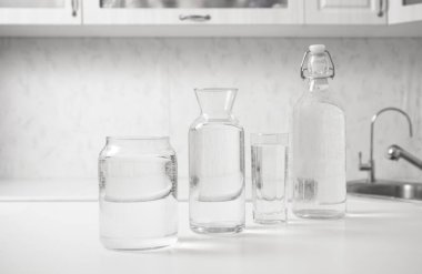 jar, bottle of water with full  transparent glasses on white table. kitchen interior. Pure drinking water. Clear aqua.