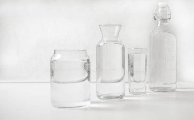 jar, bottle of water with full  transparent glasses on white table. kitchen interior. Pure drinking water. Clear aqua.