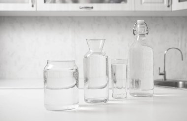 jar, bottle of water with full  transparent glasses on white table. kitchen interior. Pure drinking water. Clear aqua.