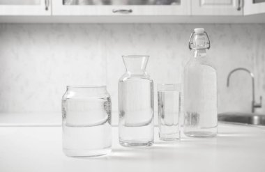 jar, bottle of water with full  transparent glasses on white table. kitchen interior. Pure drinking water. Clear aqua.