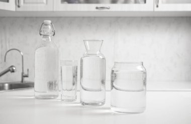 jar, bottle of water with full  transparent glasses on white table. kitchen interior. Pure drinking water. Clear aqua.