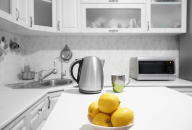 iron teapot, cup of tea,  lemons  in plate on kitchen background. Kitchen interior. Tea time concept